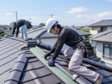 住宅屋根で補修作業をする職人